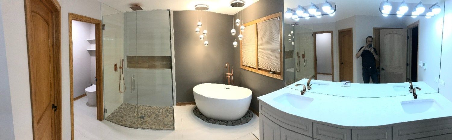 Modern bathroom with glass shower, freestanding tub, double vanity, and large mirrors