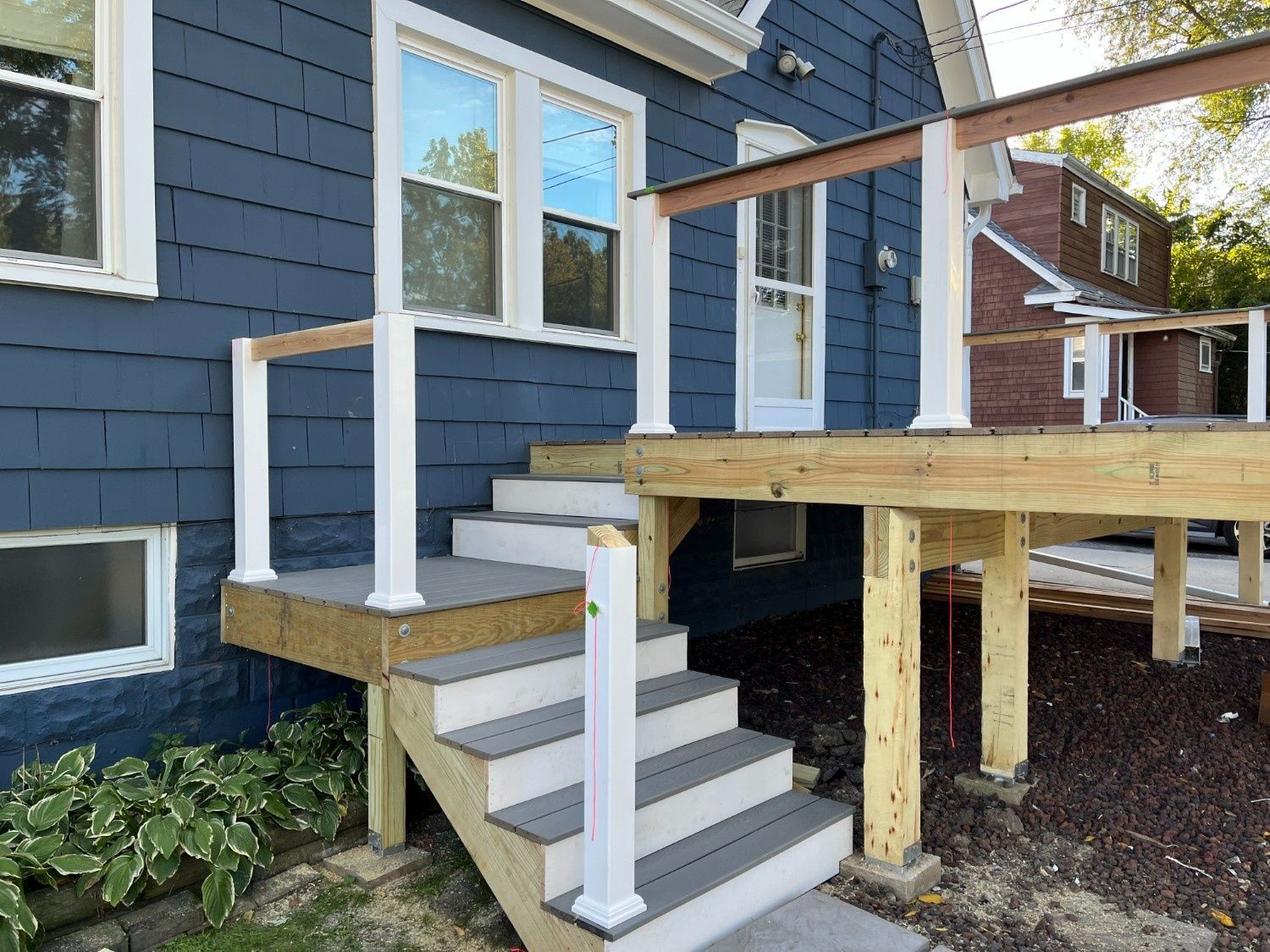 Front steps and wooden accessibility ramp attached to a blue house with white railings
