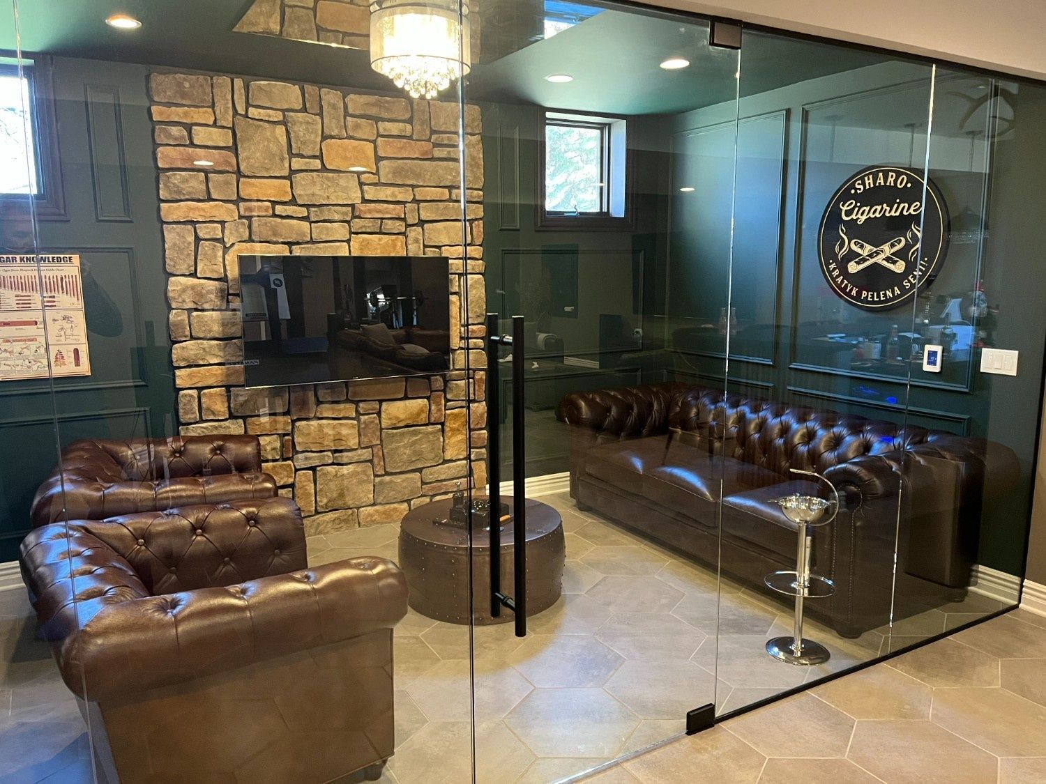 Modern lounge with leather chairs, stone fireplace, glass wall, and mirrored table.