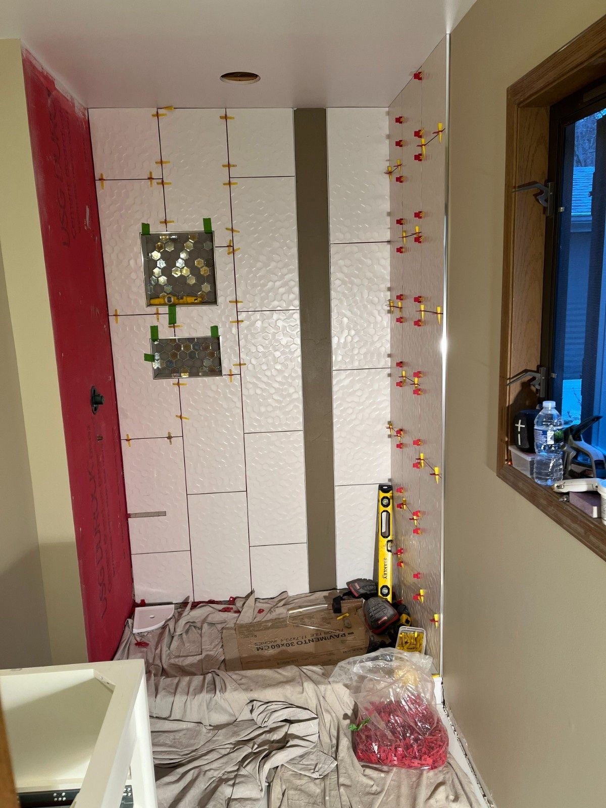 Narrow hallway under renovation with taped drywall, tools, and covered floor.