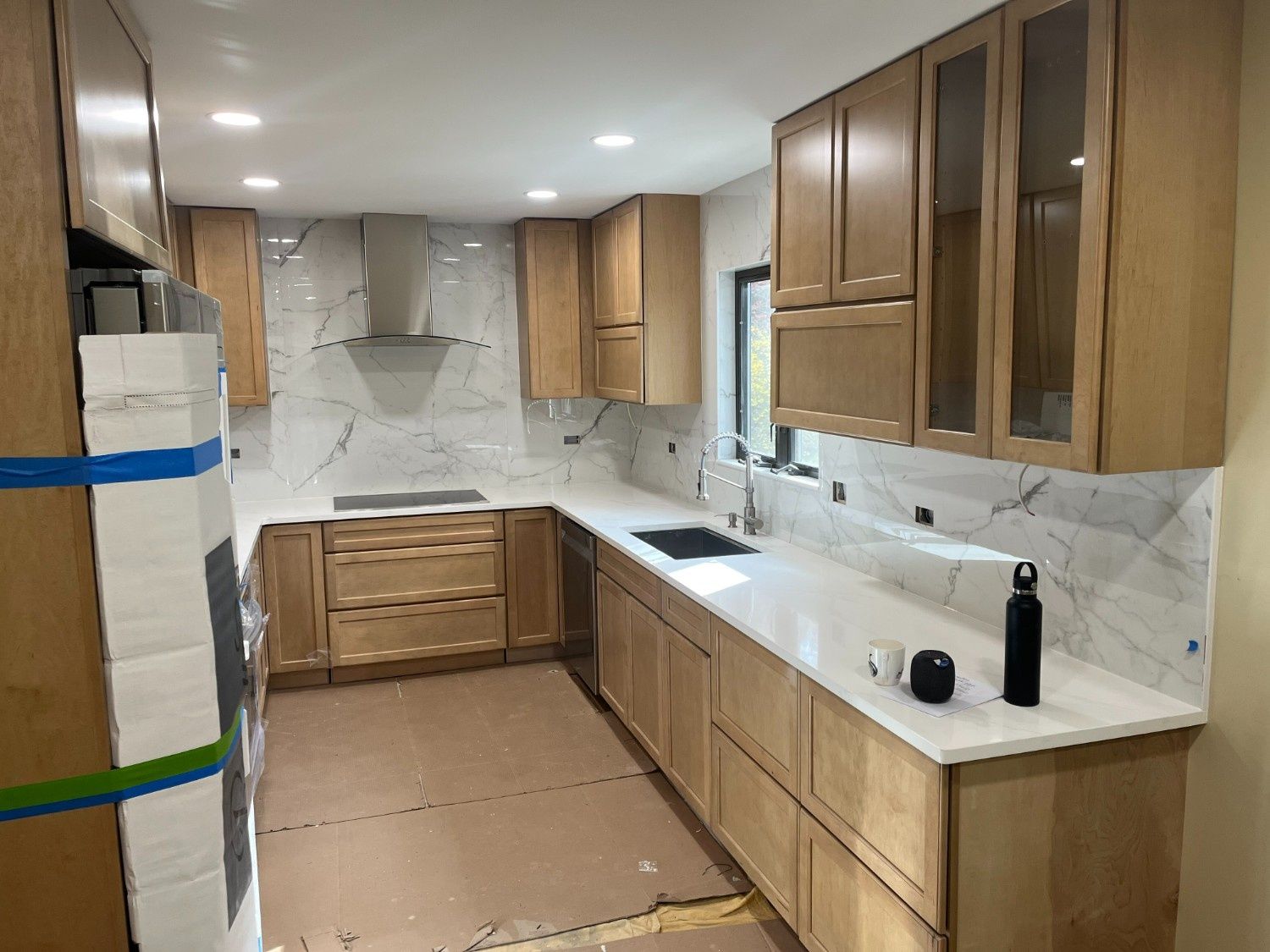 Empty kitchen with wood cabinets, white countertops, and beige flooring