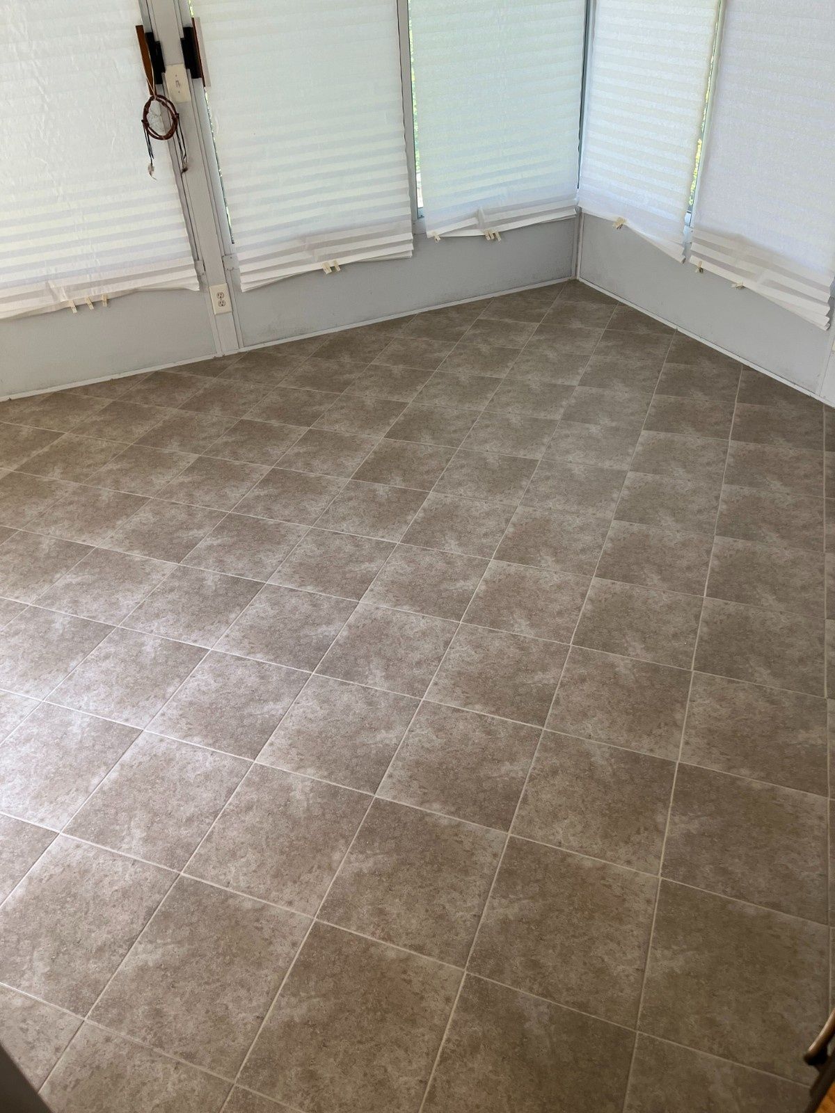 Empty room with beige tile floor and white blinds on the windows