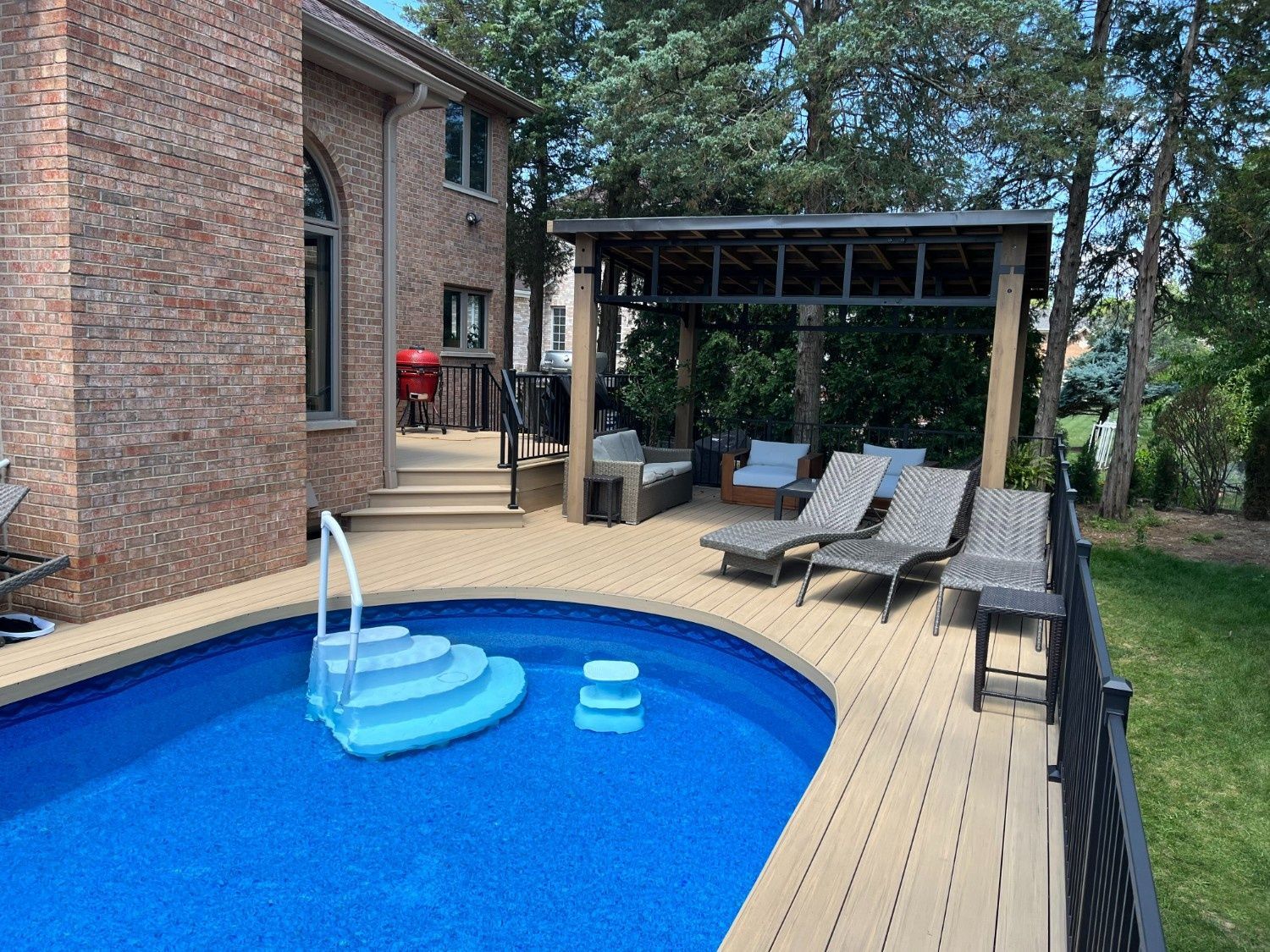 Backyard pool with blue water, lounge chairs, a covered patio, and a brick house