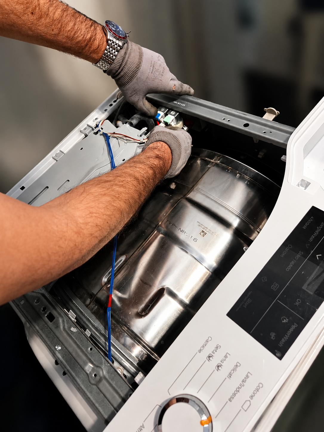 Tecnico che ripara una lavatrice in una lavanderia con prodotti per la pulizia e asciugamani piegati.
