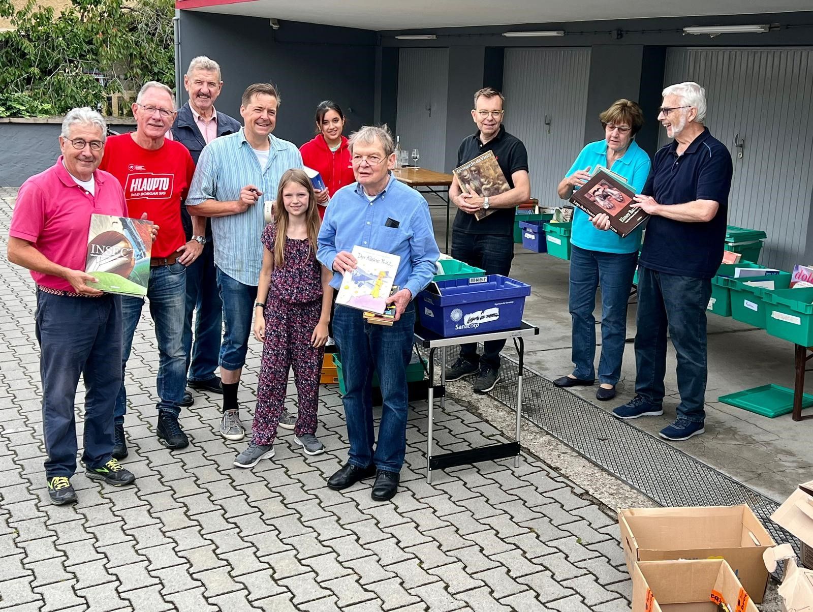 Eine Gruppe von Menschen steht nebeneinander auf einem gepflasterten Gehweg.
