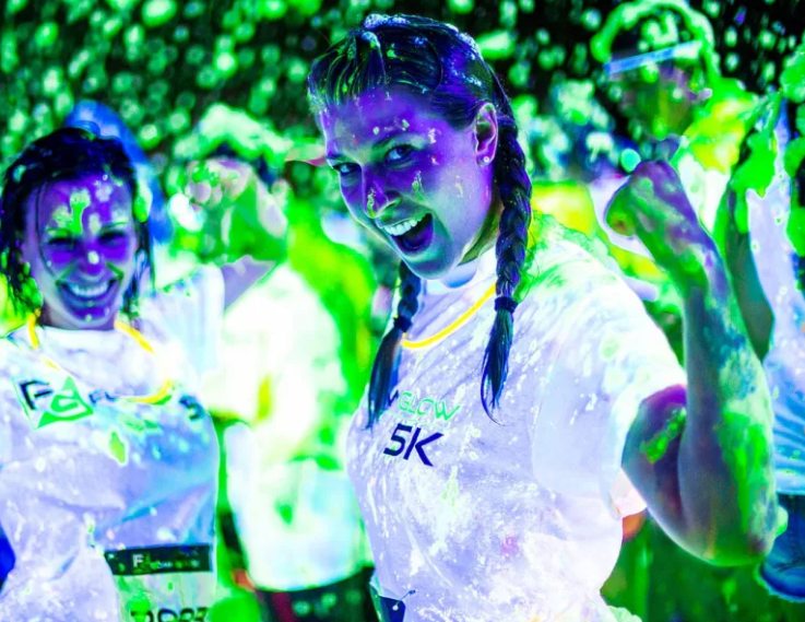 A group of people are standing in a dark room covered in glow in the dark paint.