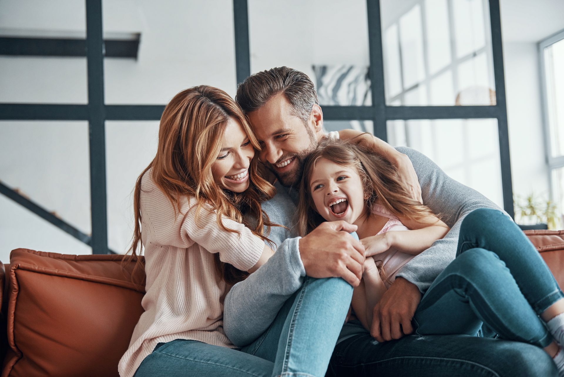 A man , woman and child are hugging each other and smiling.