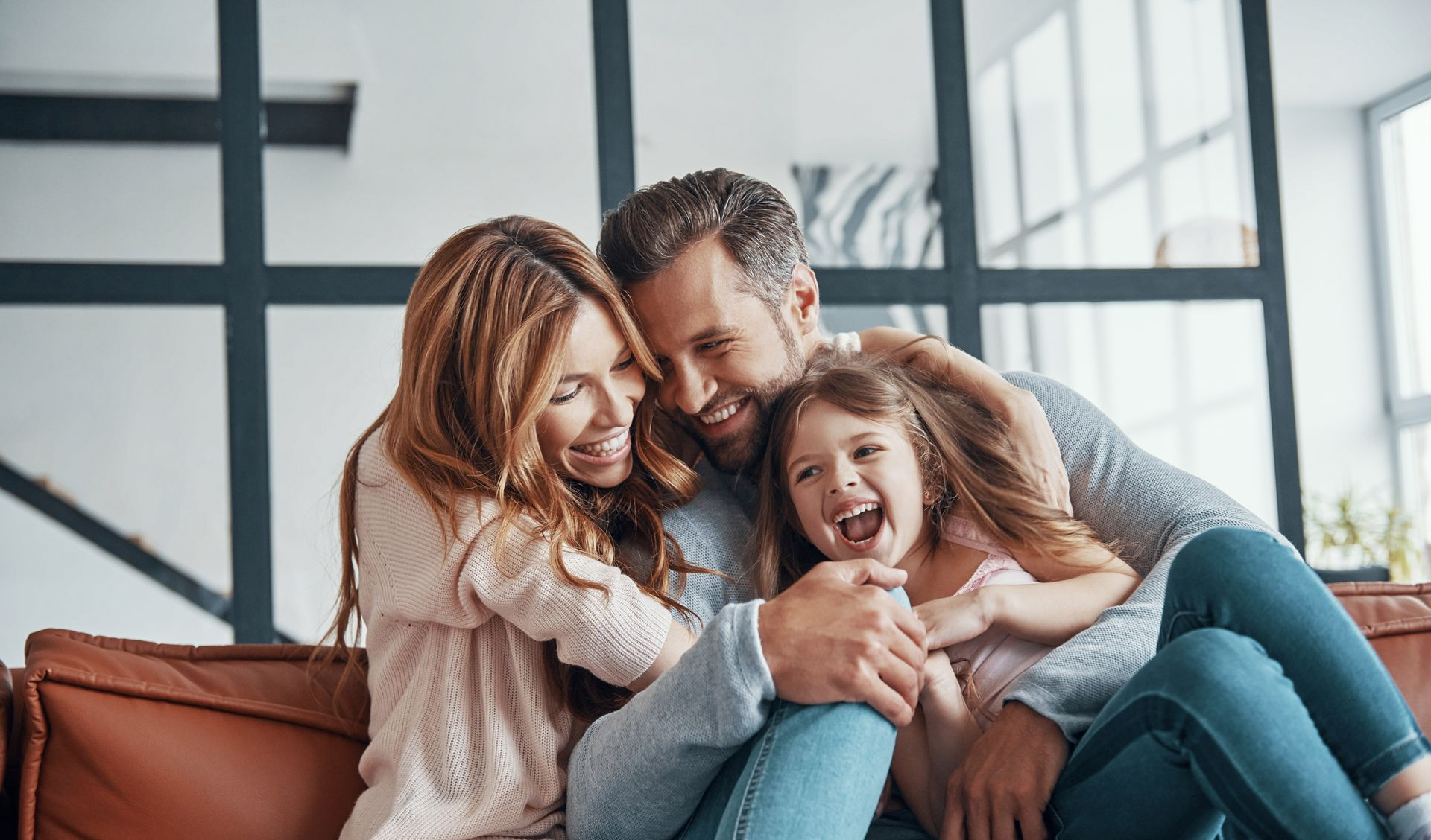 A man , woman and child are hugging each other and smiling.