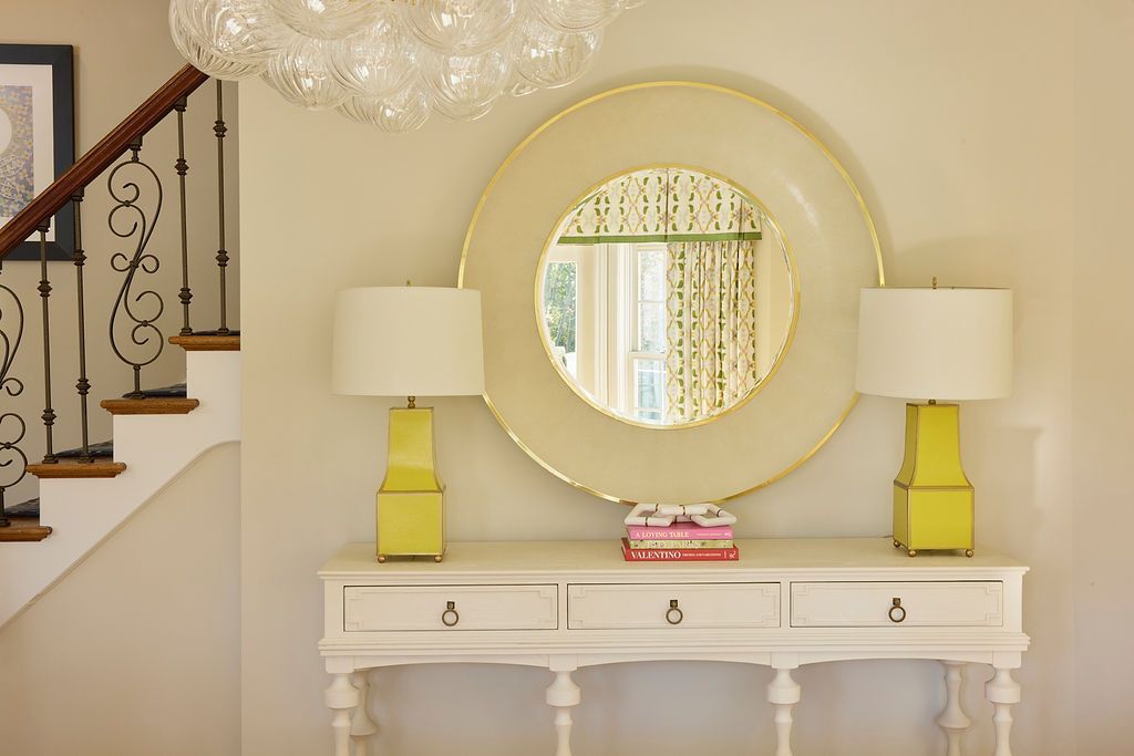 White console table with lamps and large mirror in a hallway.