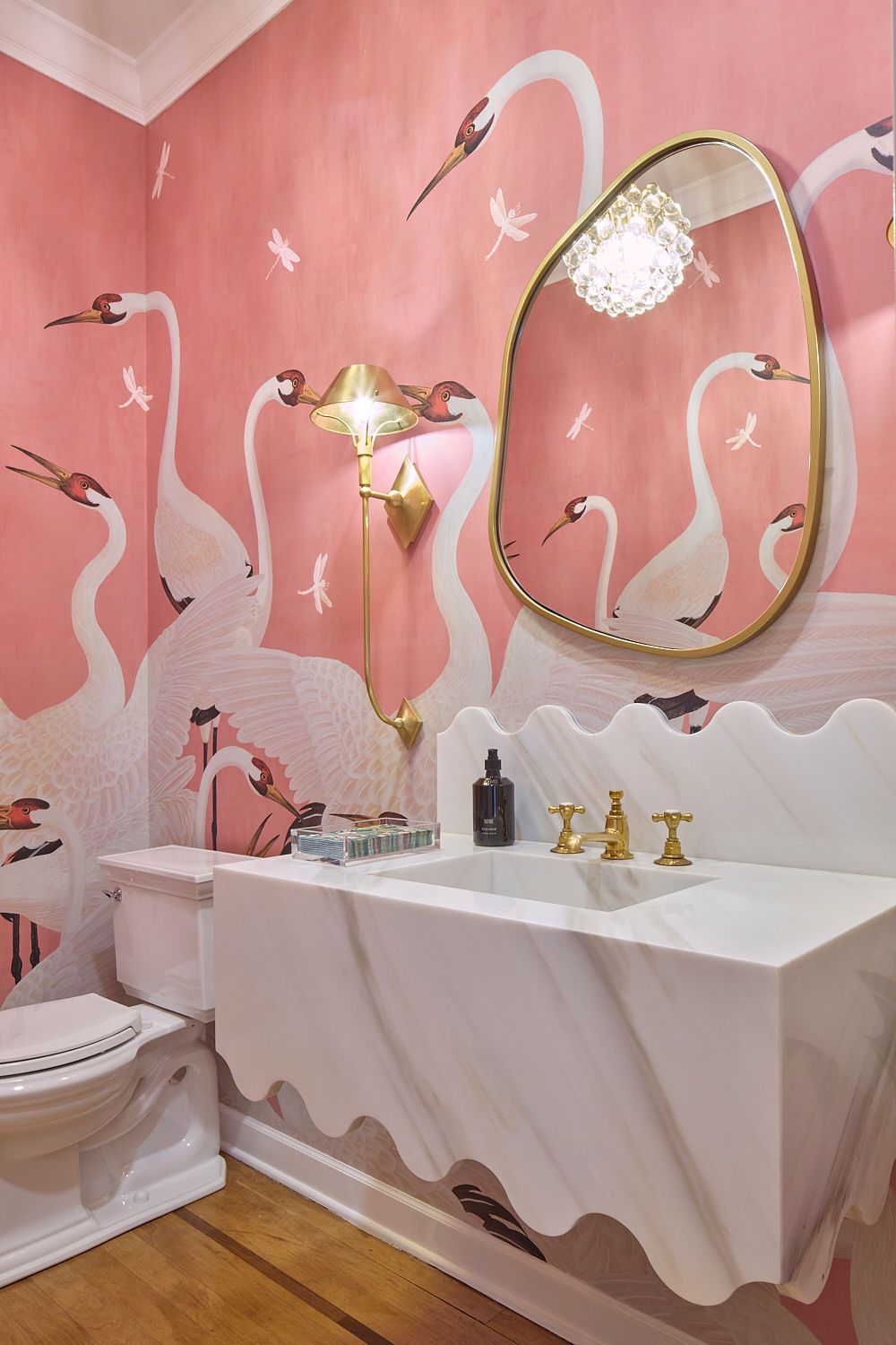 Pink swan-themed powder room with marble sink, gold fixtures, and ornate mirror.