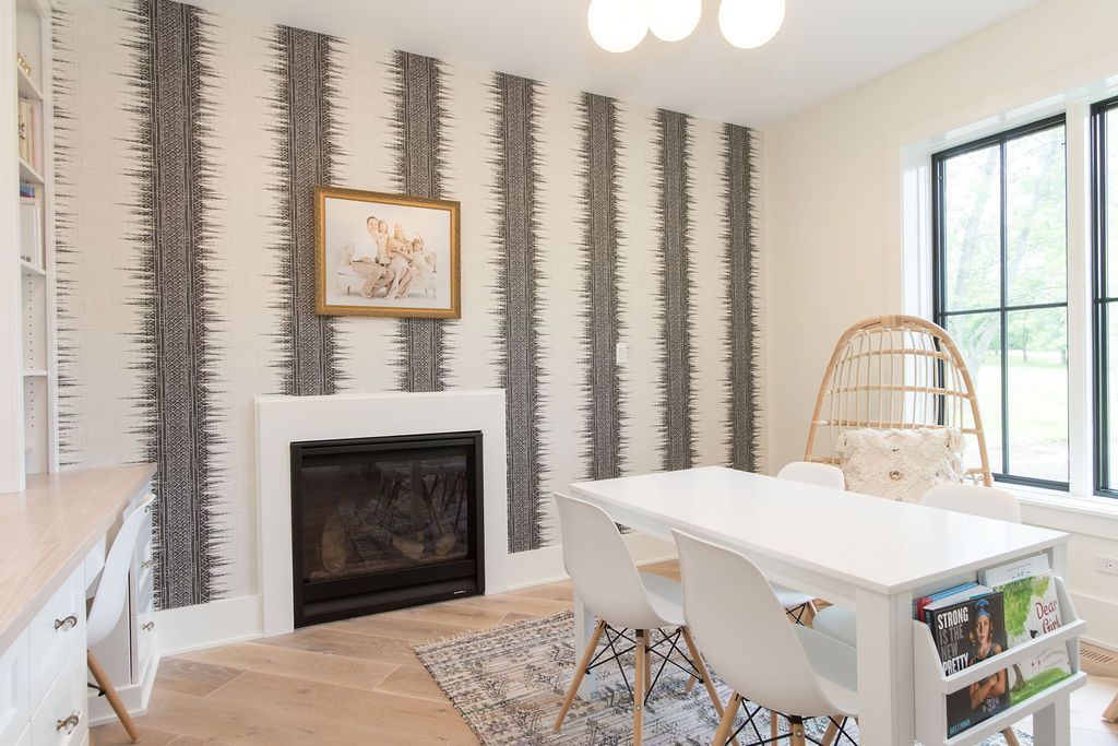 White room with fireplace, striped wall, table with chairs, and a hanging chair.