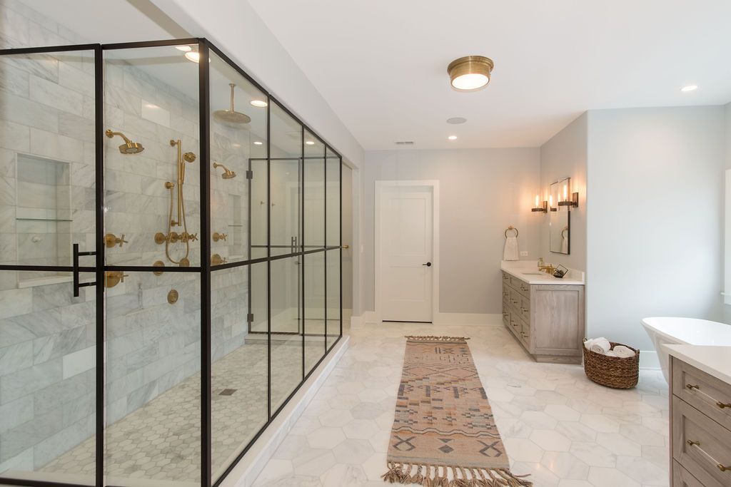 Spacious bathroom with glass shower enclosure, marble tile, and neutral colors.