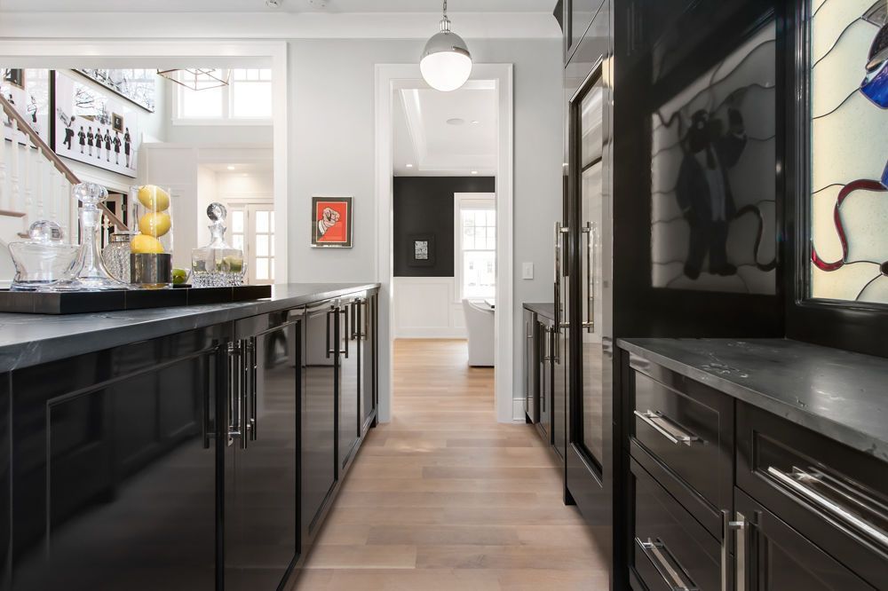 Modern kitchen with black cabinets, gray countertops, and light wood floors.