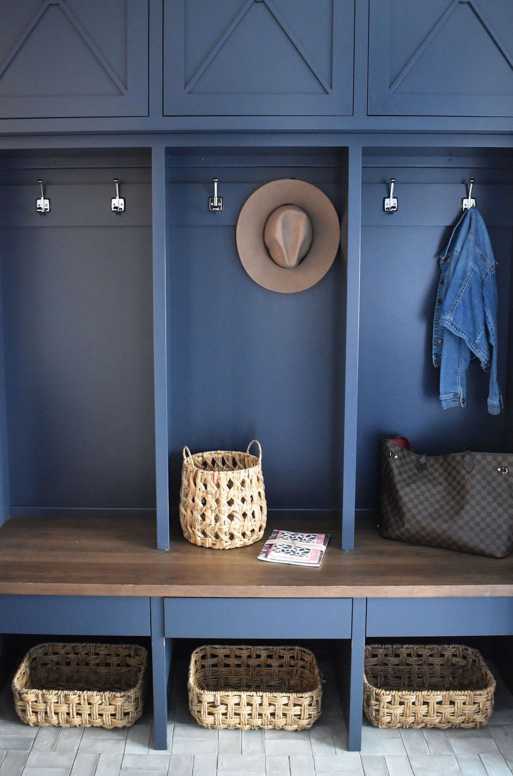 Blue built-in storage with hooks, a hat, a jacket, baskets, and a bag.