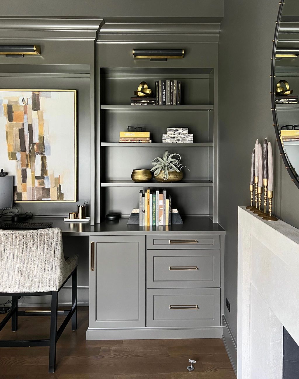 Gray built-in desk and shelving unit with books, decor, and artwork in a modern home office.