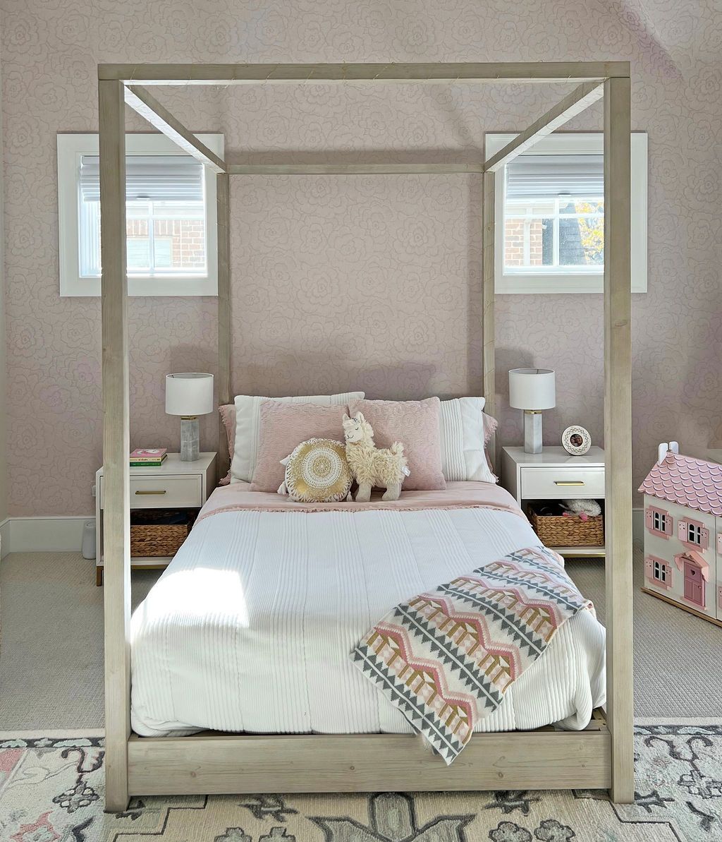 Bedroom with a light gray canopy bed, two white nightstands, and pink wallpaper.