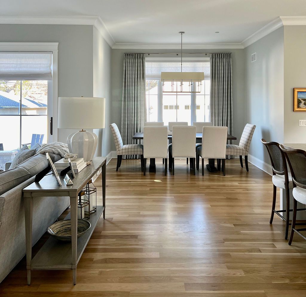Living room with dining area. Gray walls, light wood floors, and neutral furnishings.
