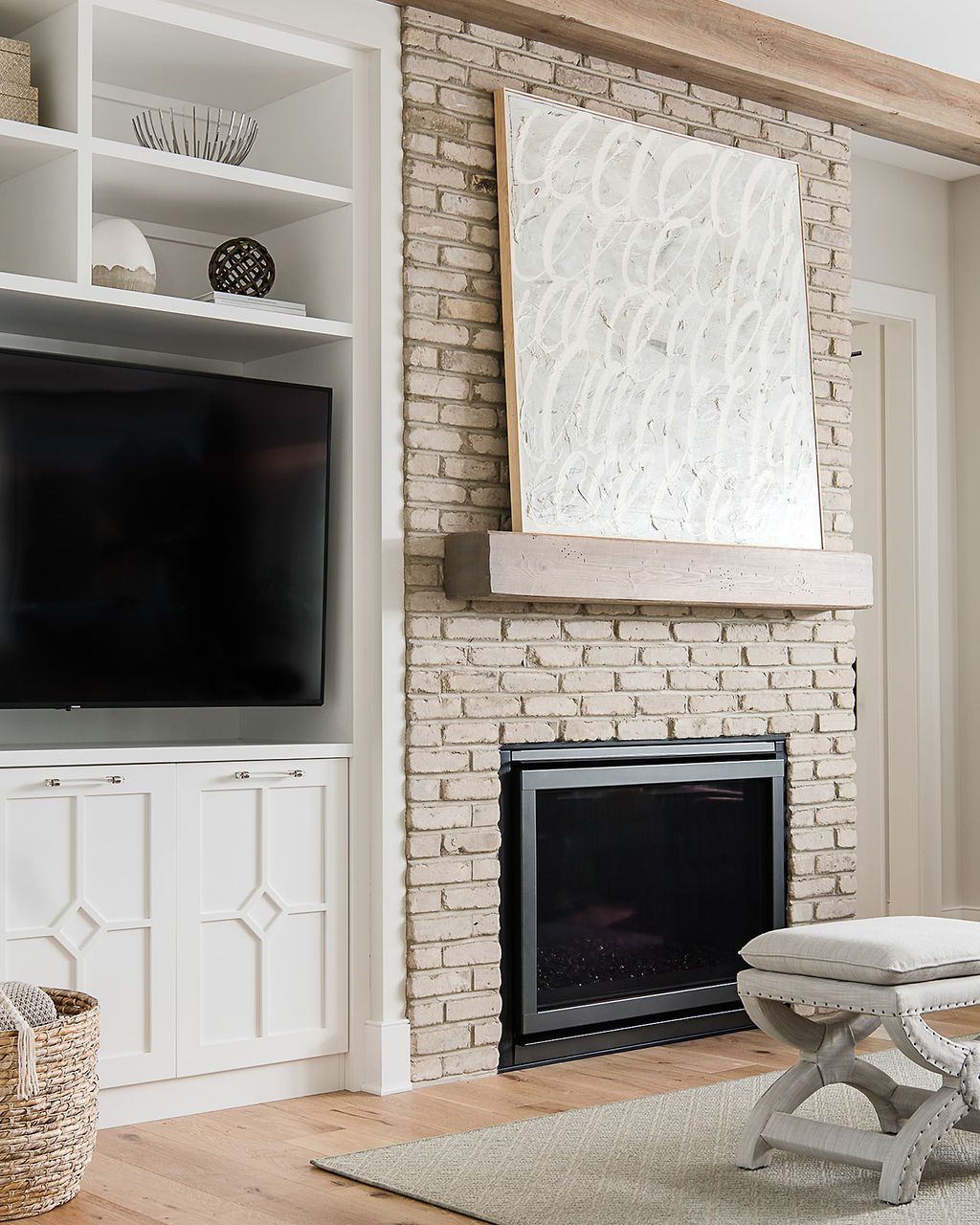 Living room with brick fireplace, built-in shelving, TV, and decorative art.