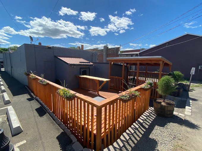 A wooden deck is surrounded by a fence in a parking lot.