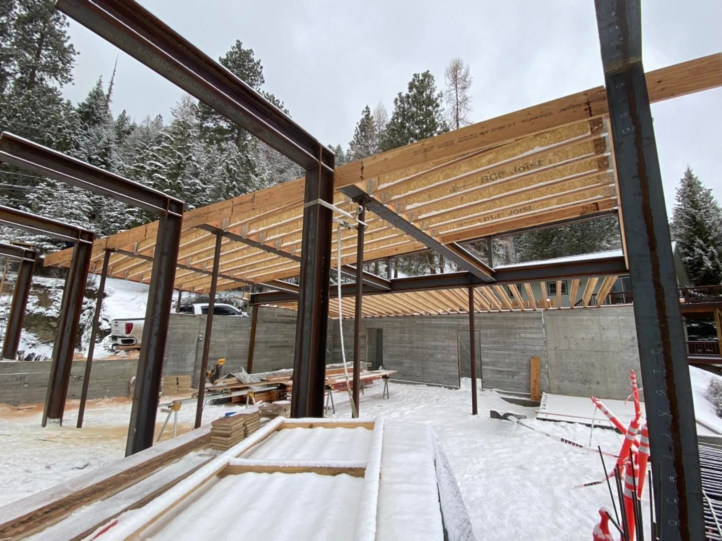 A building under construction in the snow with trees in the background.