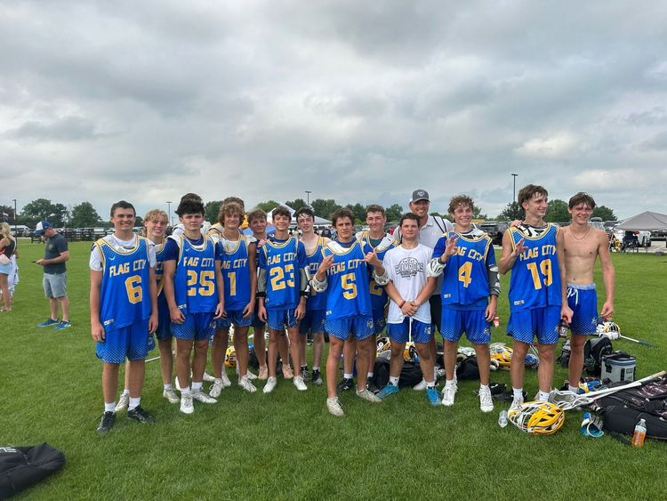 Youth football team in blue uniforms posing on a field with trophies and gear on the grass
