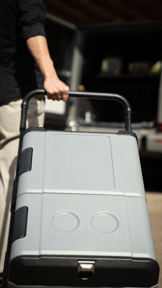 Person Carrying a Gray, Portable Cooler with Black Handle Outdoors — Lakeside Gas Fridges In Maitland, NSW