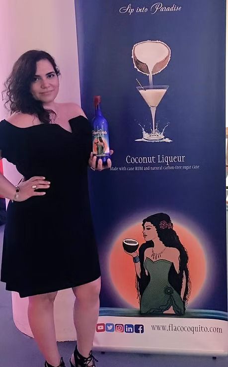Woman in black dress posing beside a cocktail-themed event banner with purple background and a martini graphic