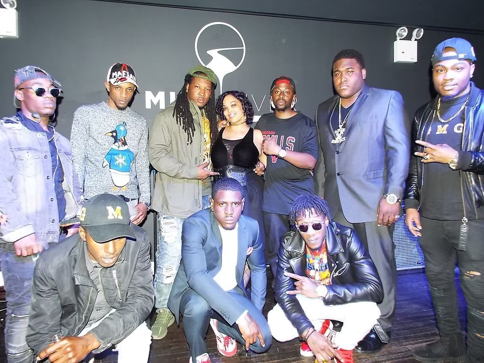 Group of people posing together in a dim club, with one man crouching in the front.