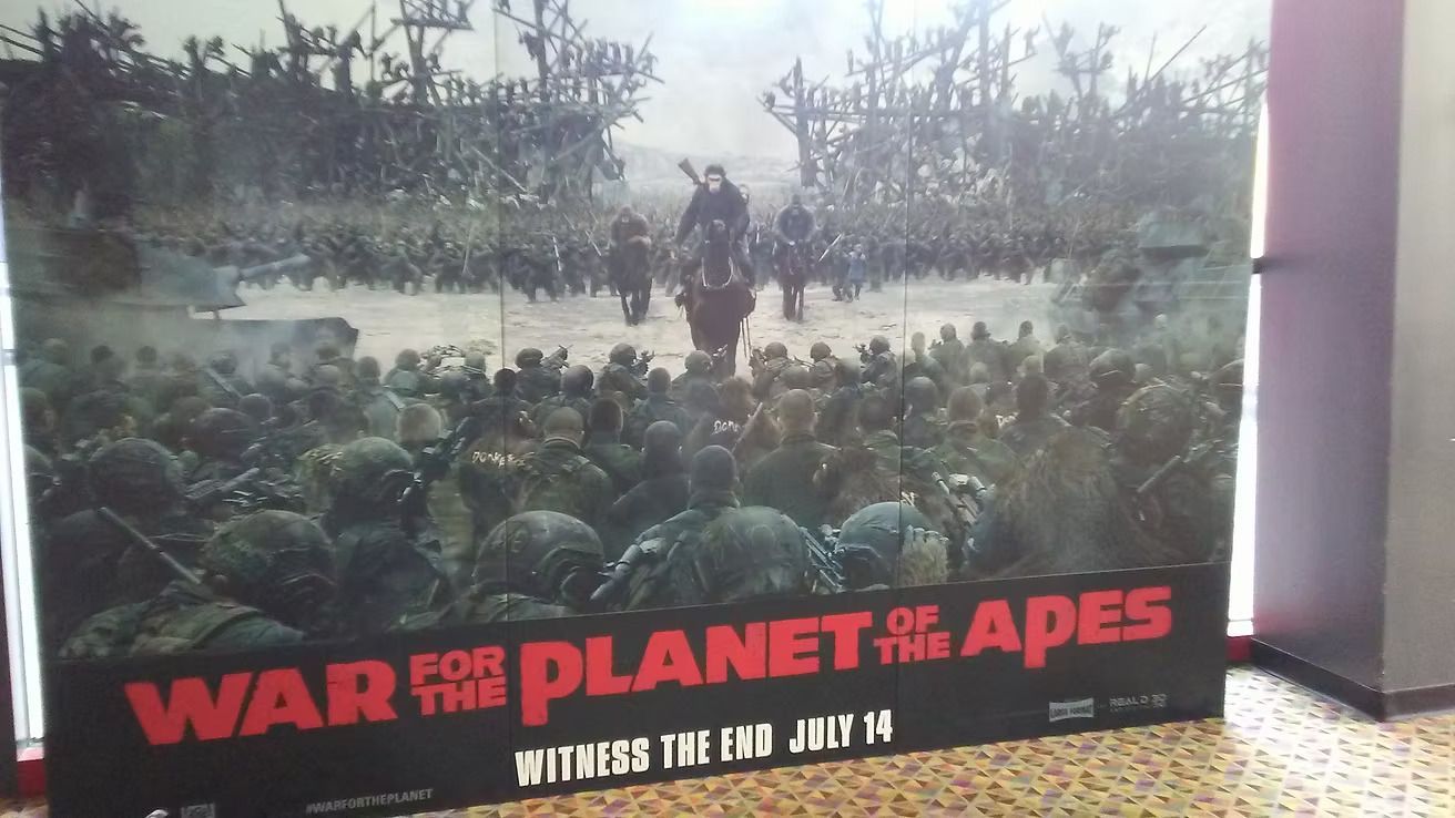 Poster for “War for the Planet of the Apes” showing a crowd of apes in a forest scene.