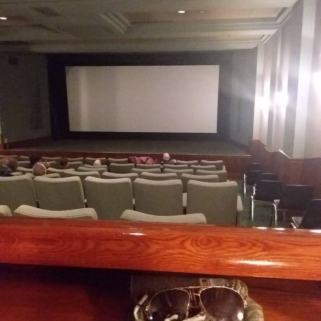 Empty movie theater with rows of seats facing a large blank screen.