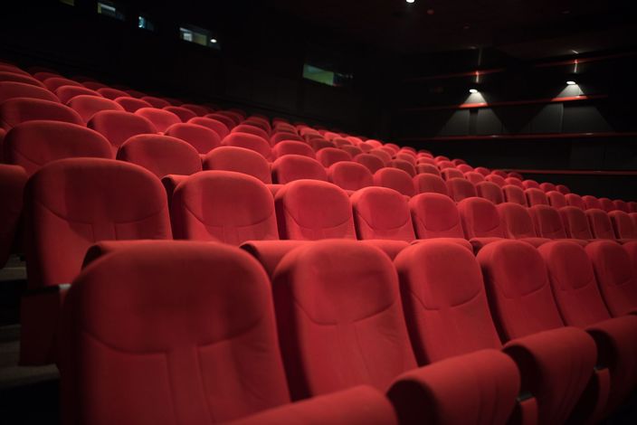 Rows of empty red theater seats in a dark auditorium