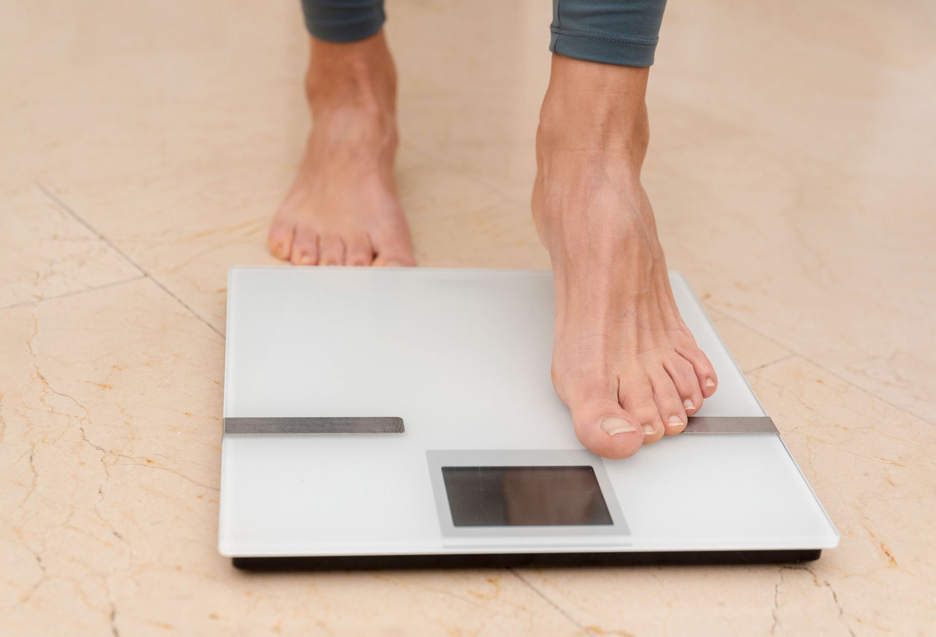 A person’s feet stepping onto a digital scale. A person’s feet stepping onto a digital scale.