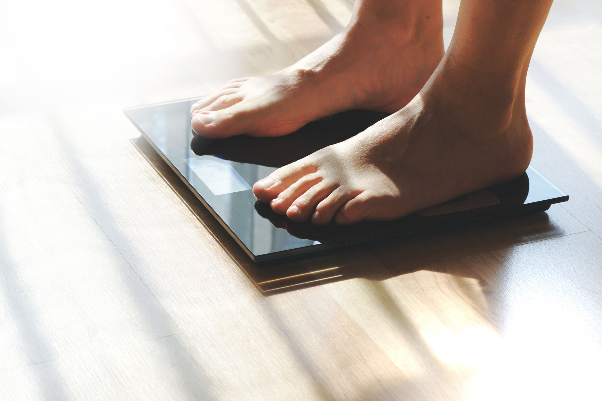 Bare feet on a glass bathroom scale during medical weight loss care in Maryville, TN