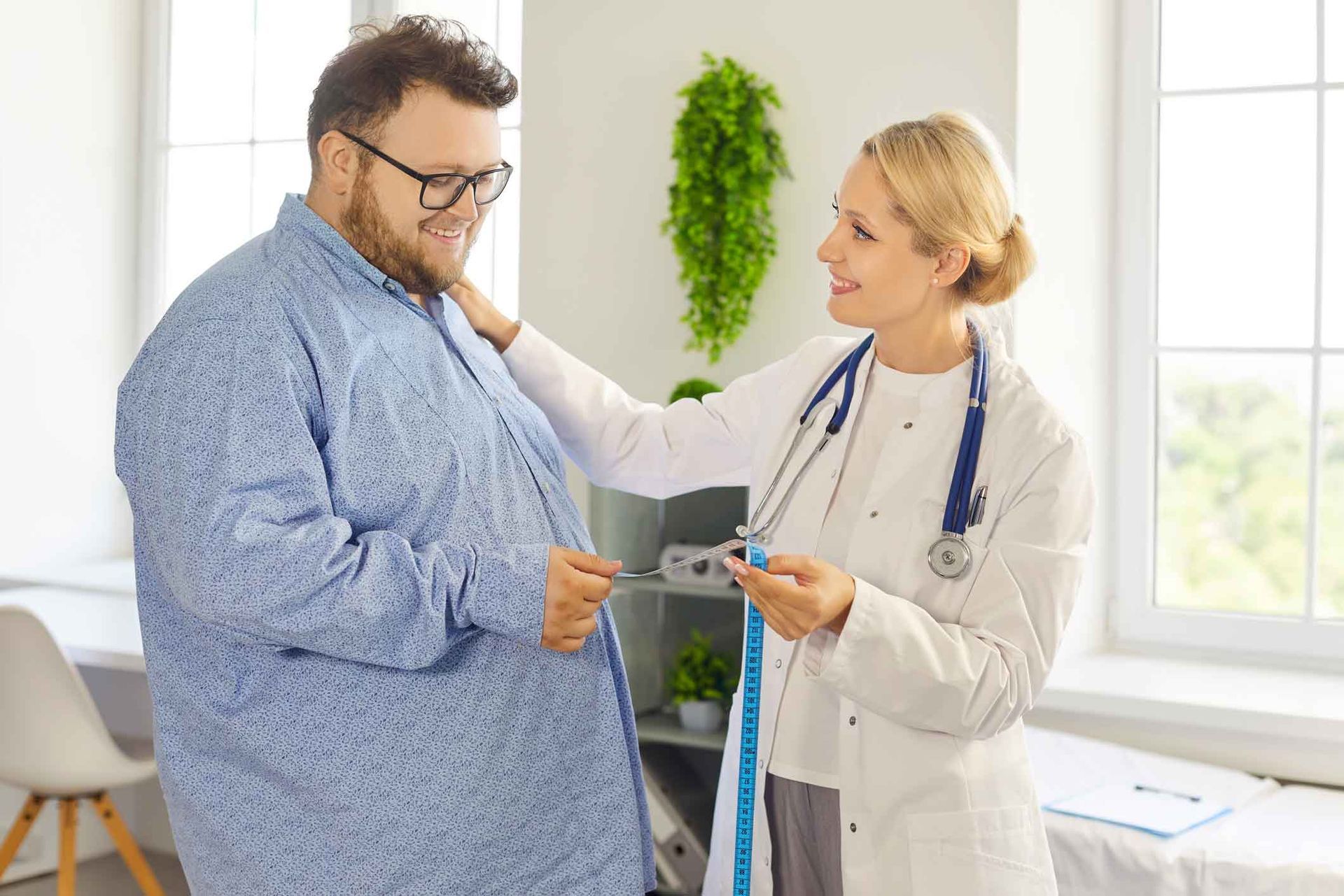Doctor measuring an overweight male patient's waist with a tape measure in a bright clinic Doctor measuring an overweight male patient's waist with a tape measure in a bright clinic