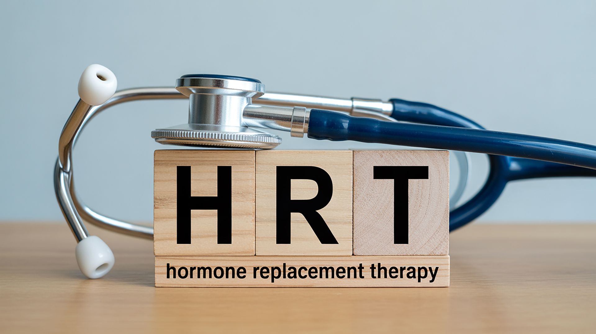 Stethoscope over wooden blocks spelling HRT for hormone replacement therapy treatment.