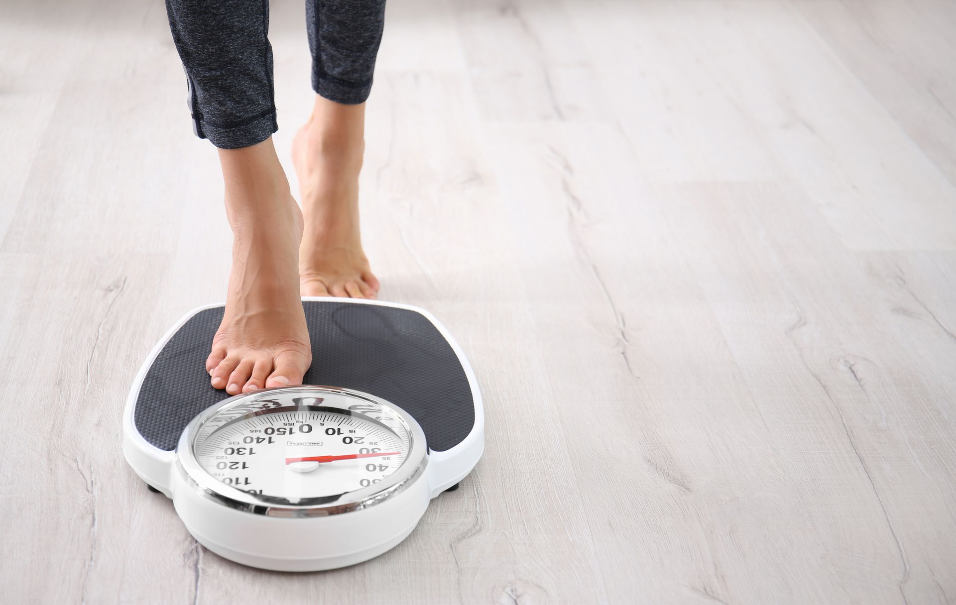A woman stands on a scale on the floor.
