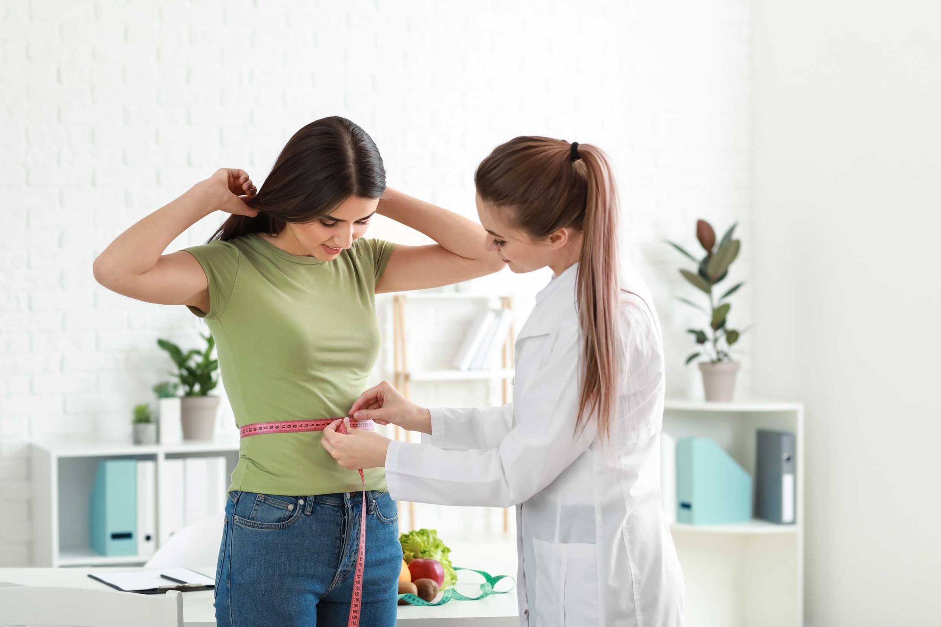 Weight loss clinic specialist measuring patient waist during personalized wellness program. Weight loss clinic specialist measuring patient waist during personalized wellness program.