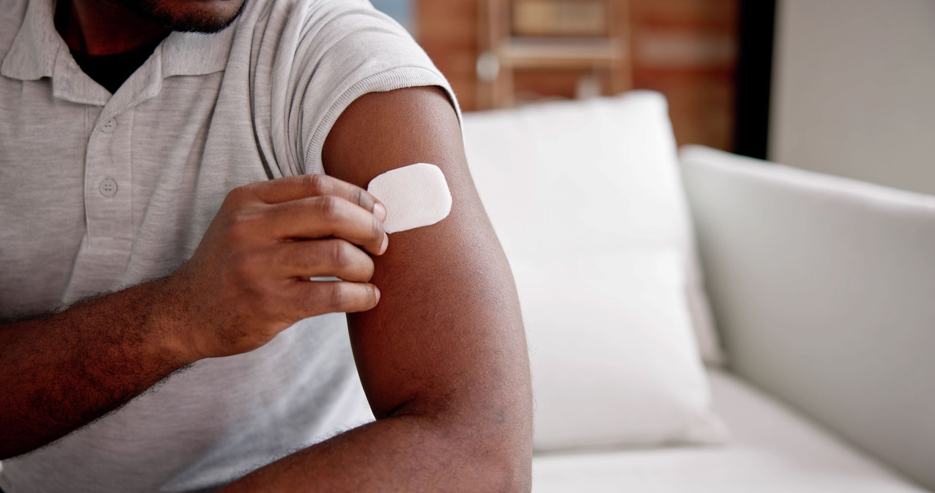 Man applying a testosterone hormone therapy patch to his upper arm at home