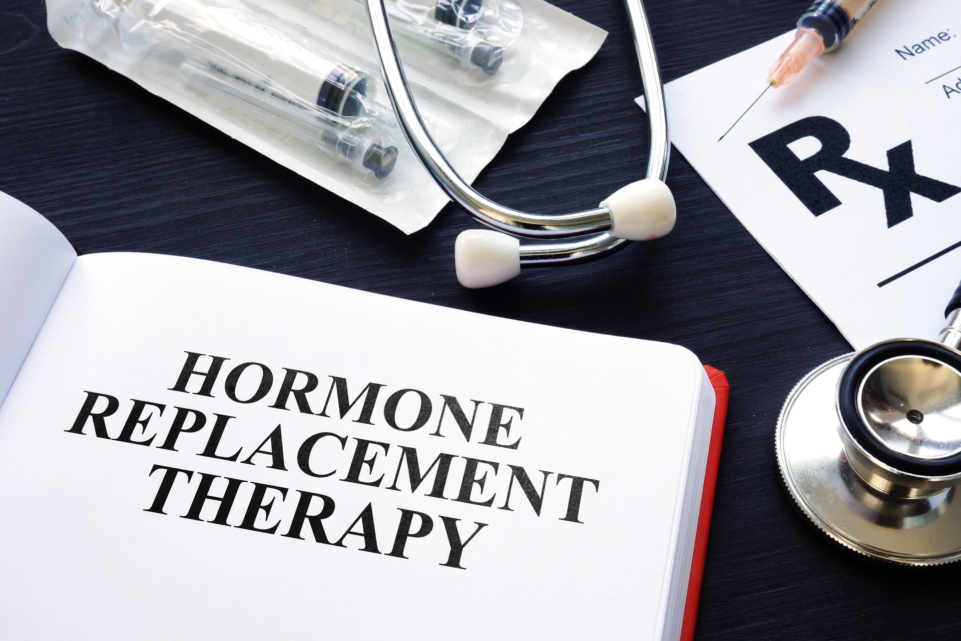 Hormone replacement therapy booklet beside stethoscope and Rx prescription form