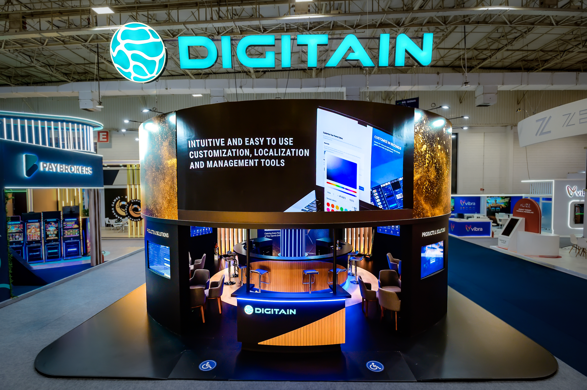 Digitain booth at a trade show, featuring a curved display, logo, and people inside.