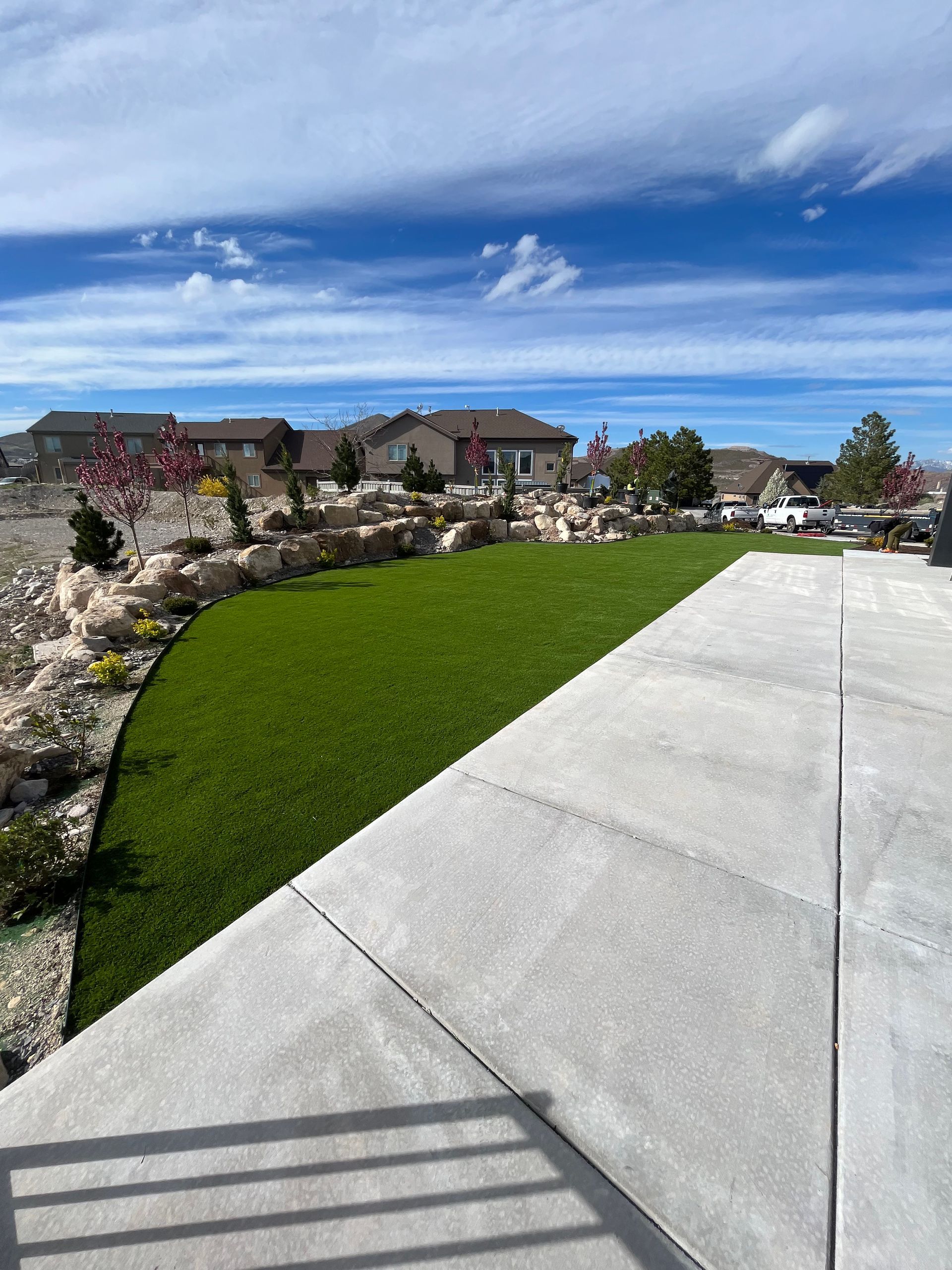 Backyard with artificial grass, patio, and white fence.