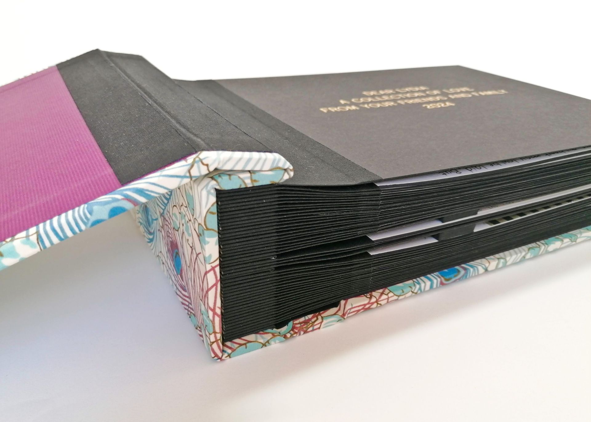 The image shows a very large album from the side with many black coloured pages bound together. The front cover of the album is hinged back to reveal the first page and the black pages are seen to have black cloth joints for added strength when turning the pages.