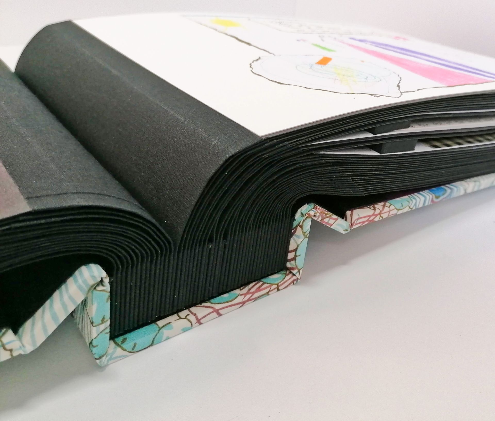 The image shows the album opened halfway and laid flat onto the table. One of the pages can be seen with a child's drawing.