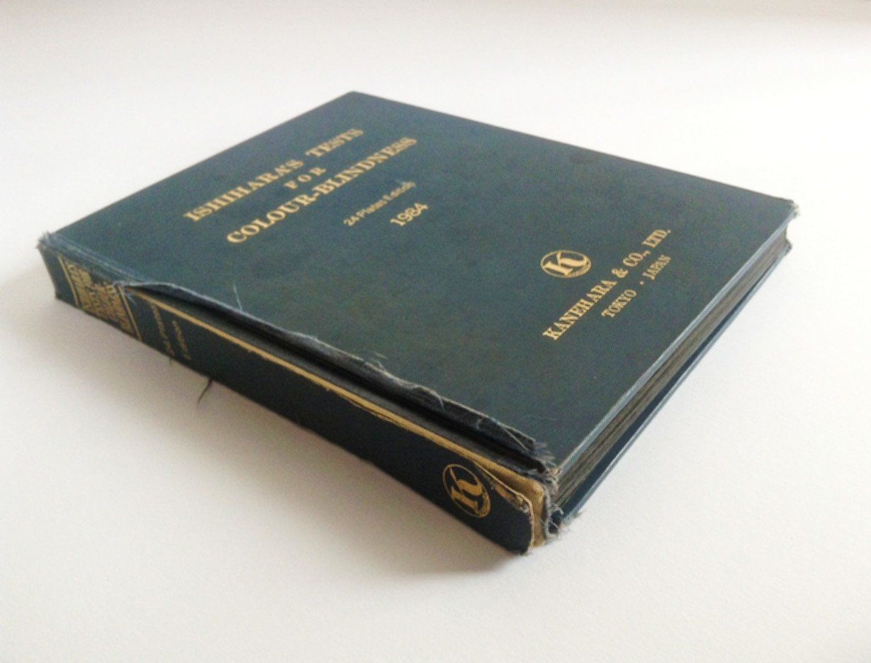 The image shows a dark blue coloured book with gold lettering on the front cover. The book is damaged and very scruffy where the hinges of the book are torn causing the spine to be loose.