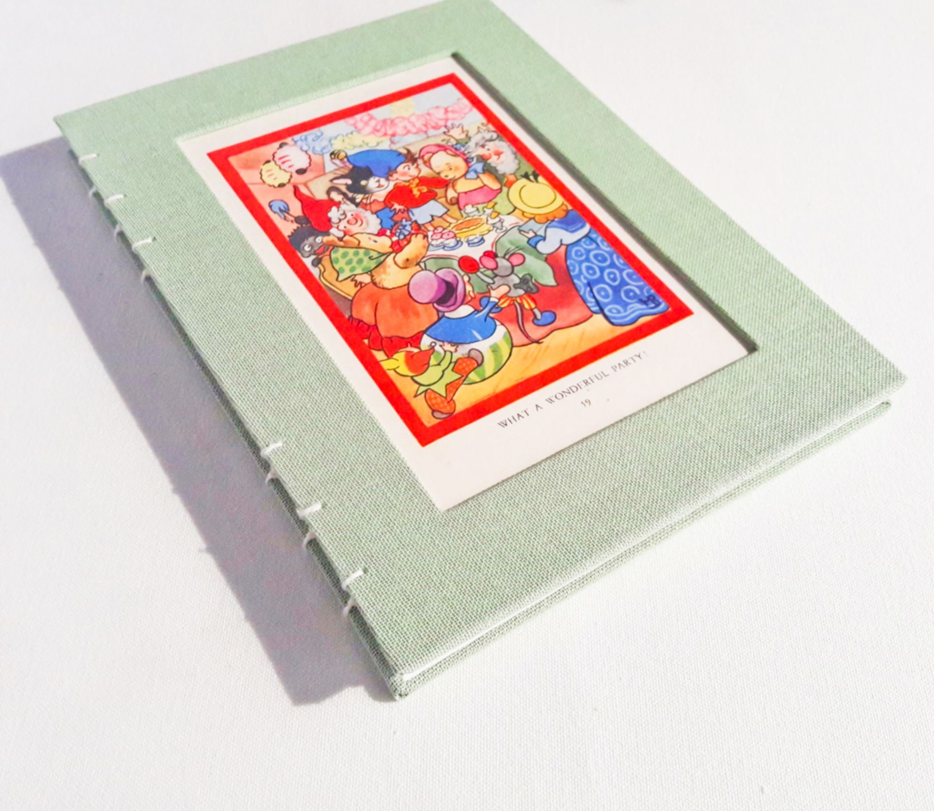 The image shows a page from a 'Noddy' children's book which has been made into a book cover on a light green textile book.