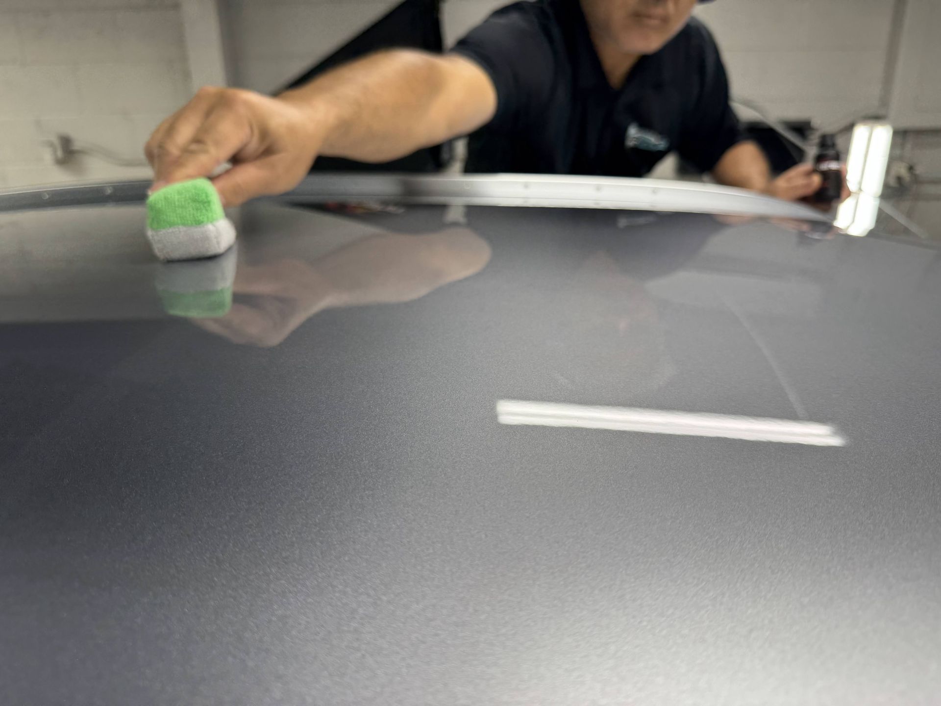 Person cleaning a reflective table with a sponge in an indoor setting
