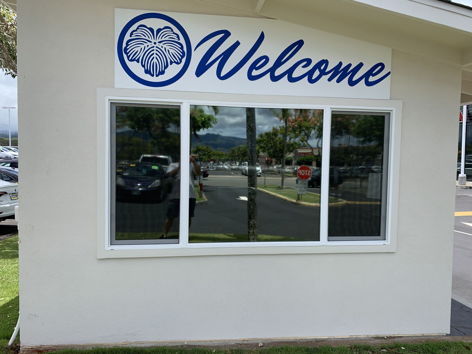 Storefront window with blue “Welcome” sign and logo above it