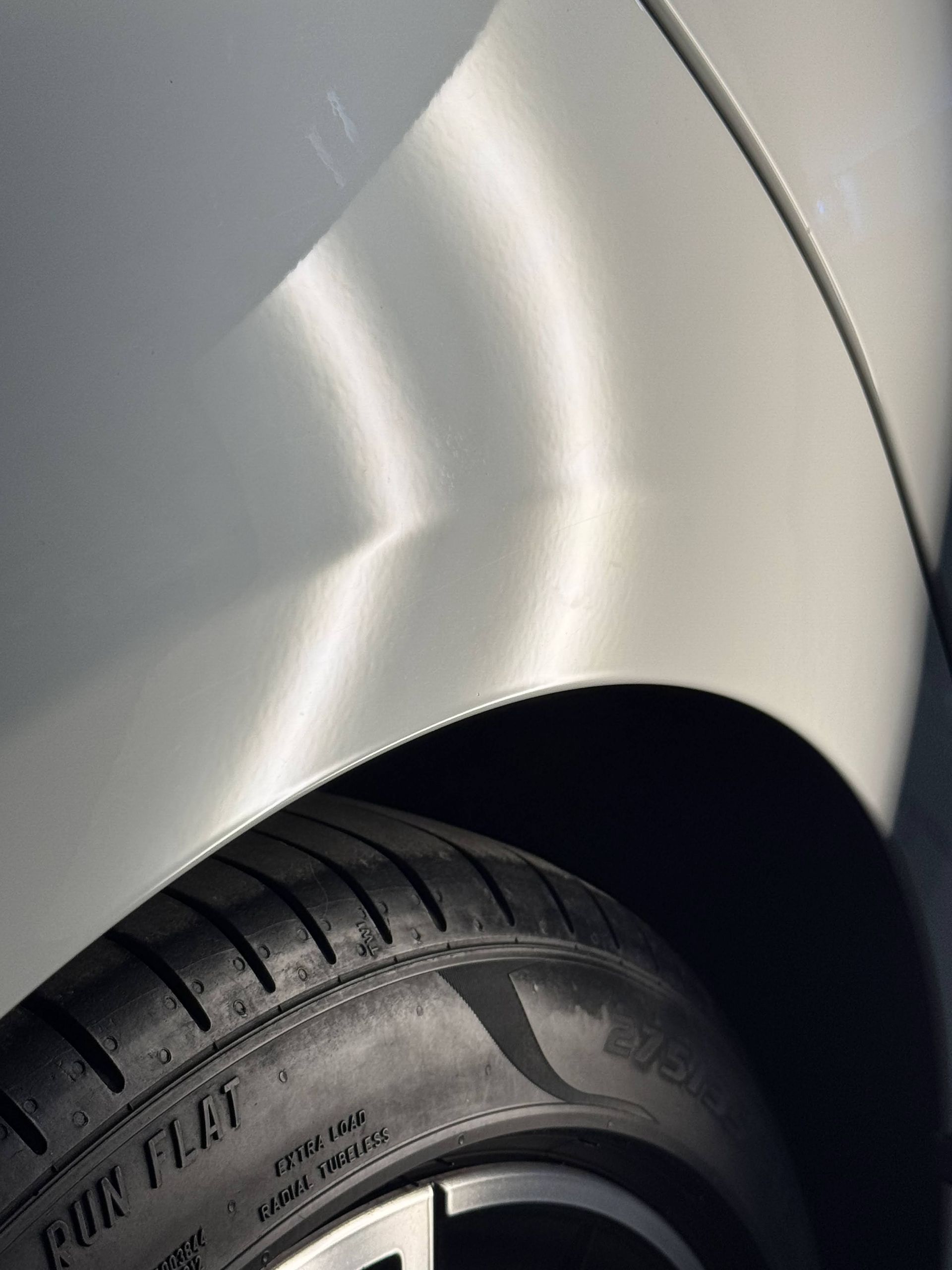 Close-up of a silver car’s rear wheel and tire under the fender