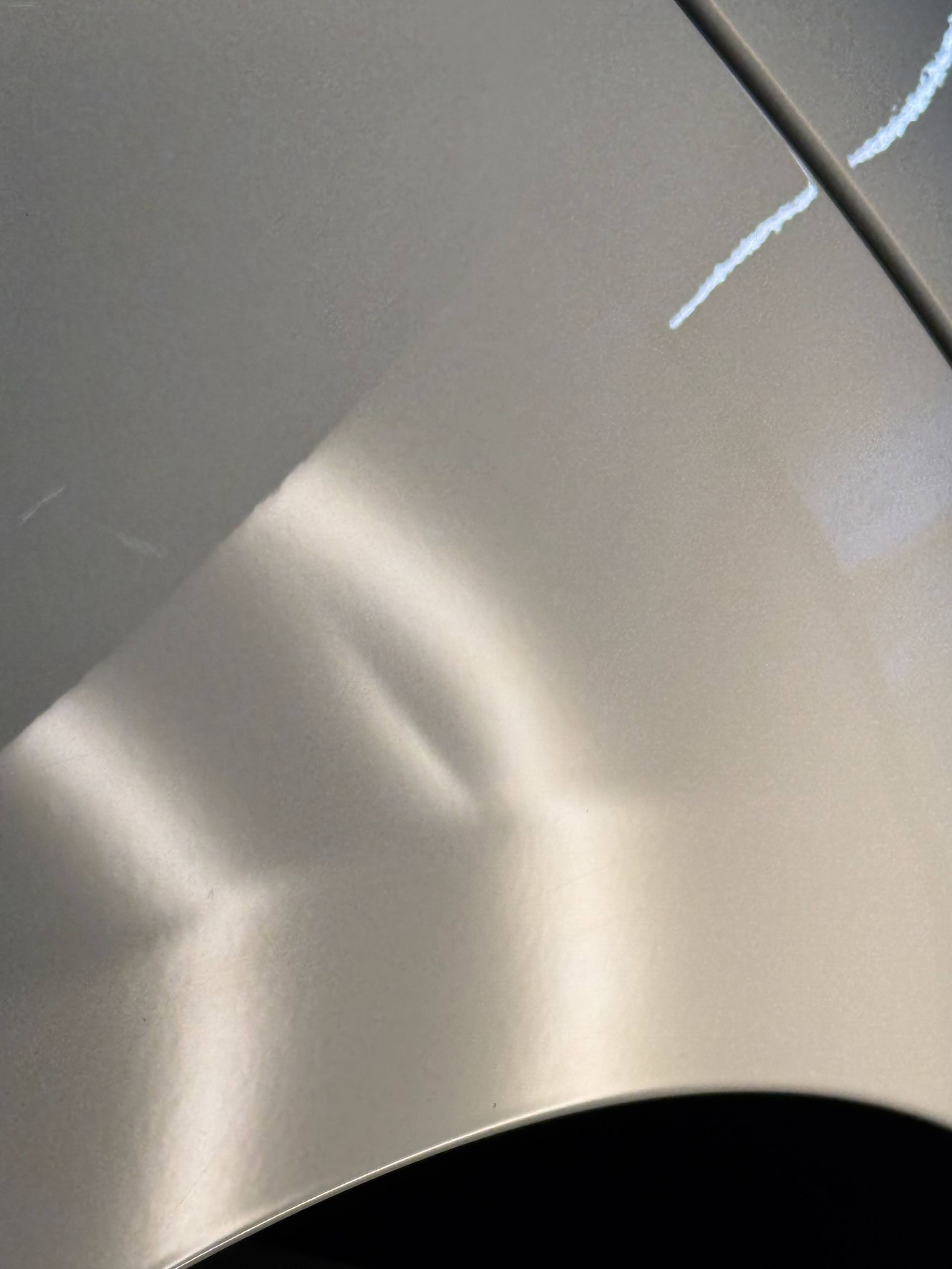 Close-up of a silver car door with a visible scratch near the wheel arch.