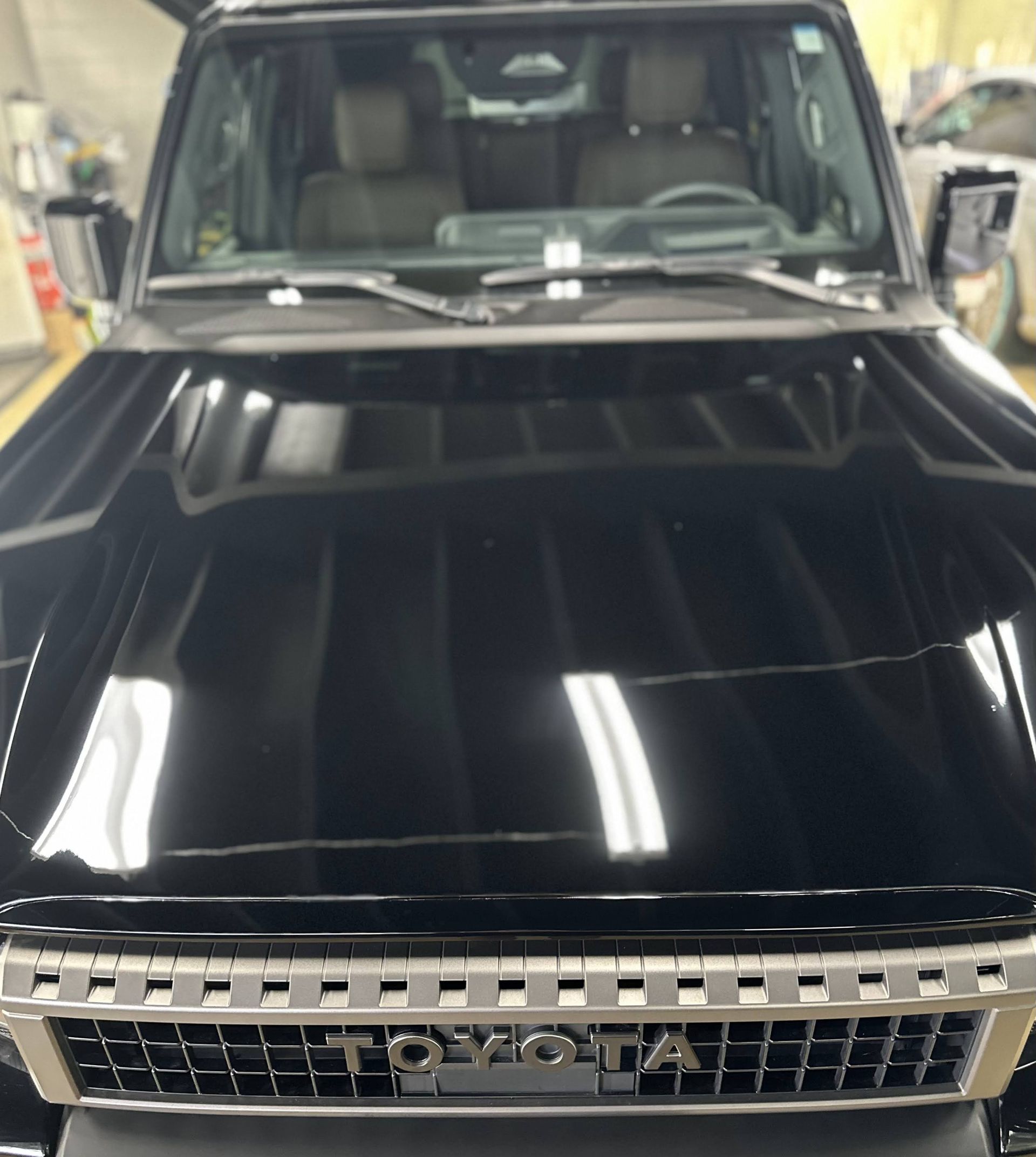 Front view of a black Toyota SUV in a garage, with glossy hood and grille visible